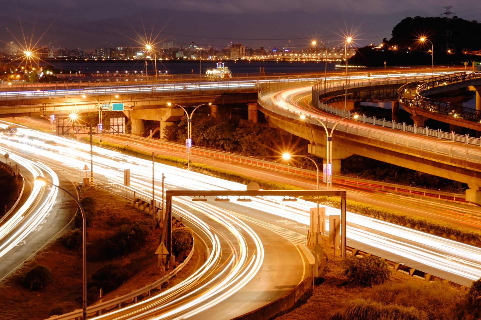 A glowing time-lapse image representing urban trafic flow along a busy freeway in neon orange.
